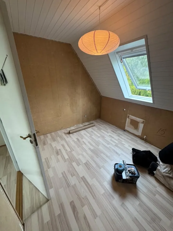 Værelse med træplader og ovenlysvindue