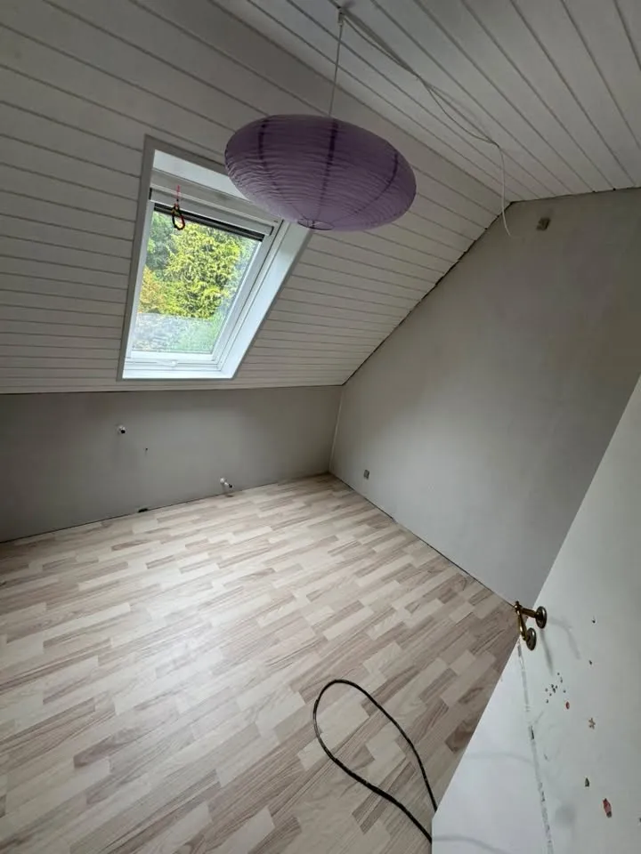Lyst værelse med skråloft og lampe