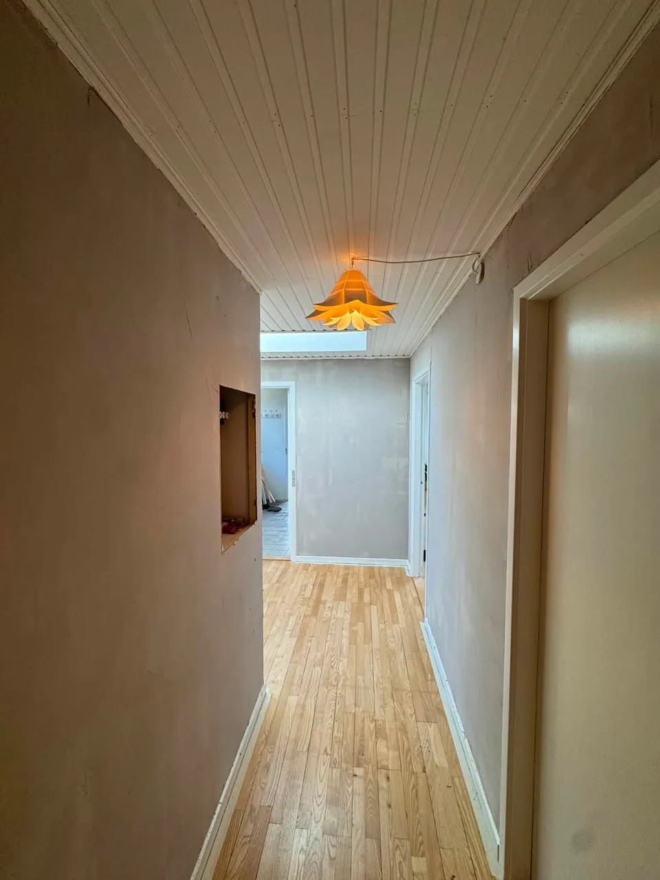 Gang med træloft og lampe